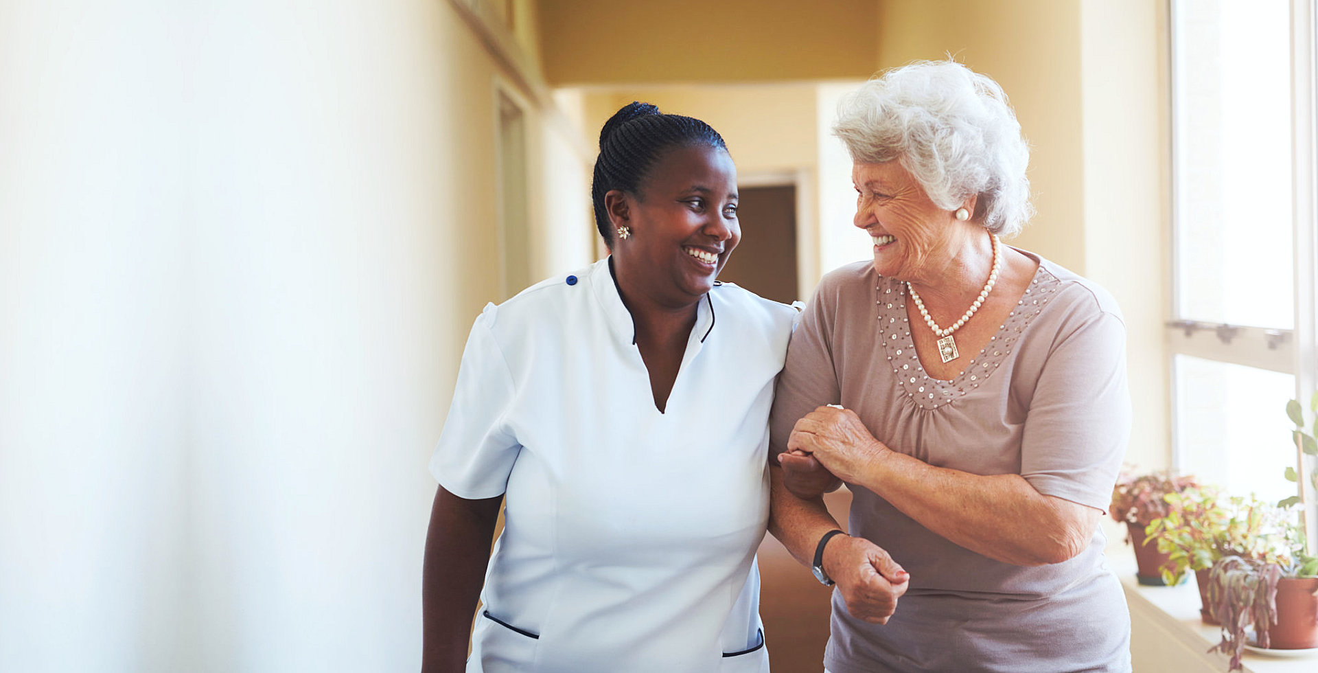 caregiver and senior woman walking at the hallway